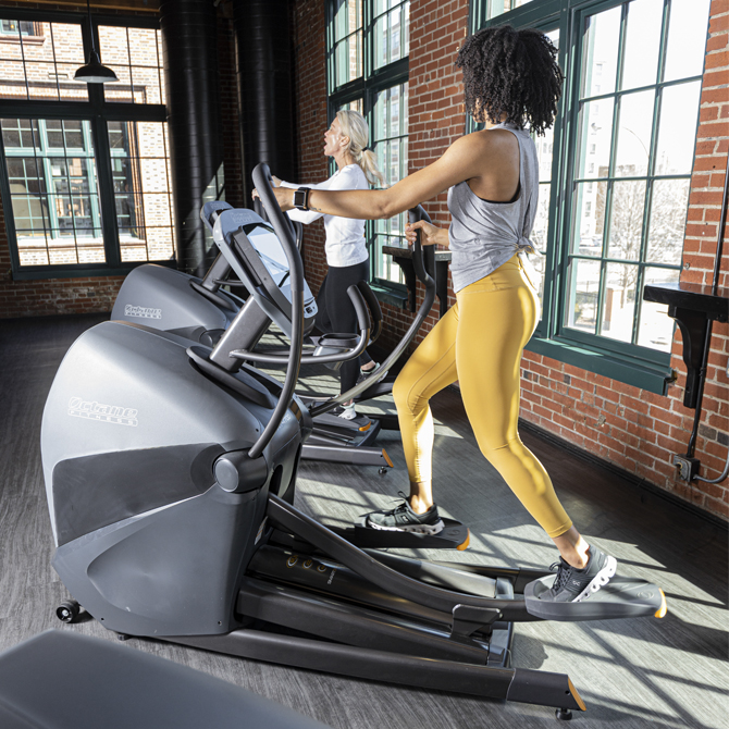 Two women working out together on XT4700 standing ellipticals - side view