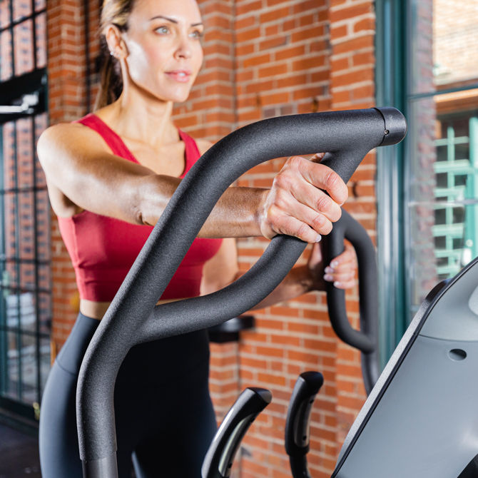Woman working out on the XT3700 standing elliptical - front view with an upper body focus