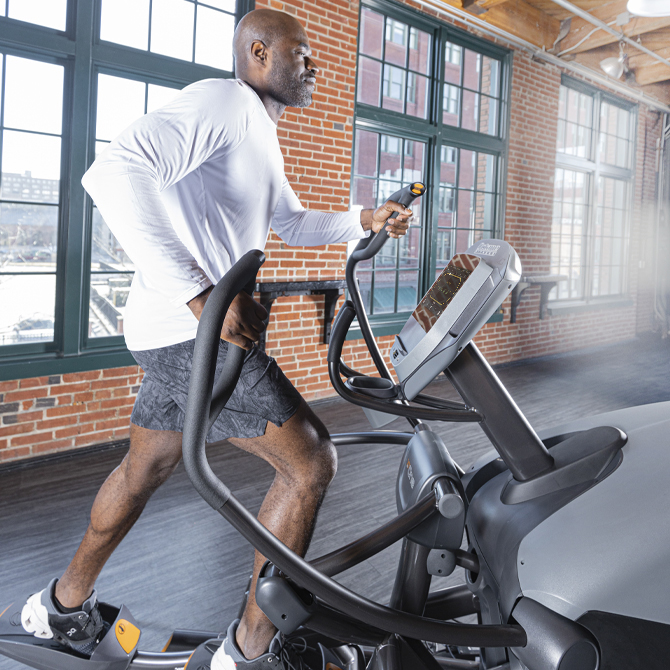 Man working out on the XT-One standing elliptical - side view with full body focus